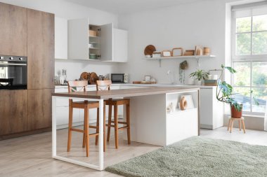 Masası, tezgahı ve dolabı olan aydınlık mutfağın içi.