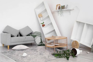 Depremden sonra alt üst olmuş koltuklu dağınık oturma odasının içinde.