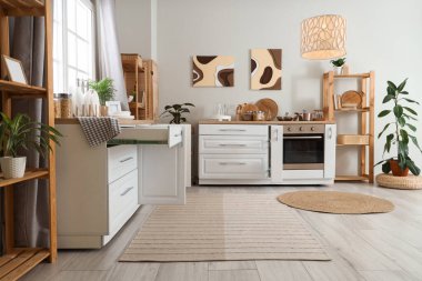 Mutfağın içi tezgah, raf üniteleri ve resimlerle dolu.