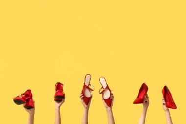 Sarı arka planda yüksek topuklu şık kırmızı topuklu kadın elleri