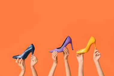 Renkli arka planda yüksek topuklu şık ayakkabılı kadın elleri