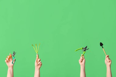 Yeşil arka planda bahçe aletleri olan kadın eller