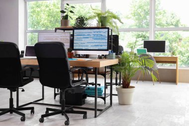 Masaları ve bitkileri olan programcı ofisinin içi