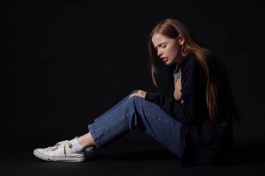 Siyah arka planda panik atak geçiren genç bir kadın.