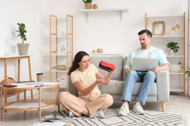 Evde dizüstü bilgisayar kullanırken kocasına boş cüzdan gösteren genç bir kadın. İflas kavramı