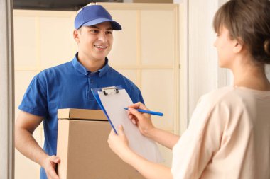 Teslimatçı, kapıdaki kadına bir paket veriyor.