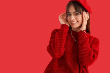 Renkli arka planda kırmızı elbiseli şık bir genç kadın.