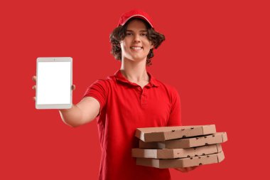 Kırmızı arka planda karton pizza kutuları ve tablet bilgisayarı olan erkek kurye.