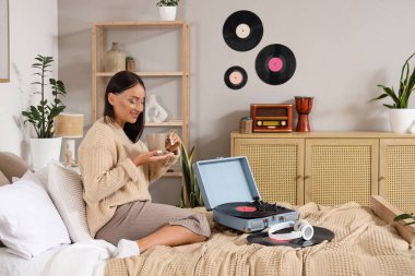 Bir fincan kahve ve pikaplı güzel bir kadın yatak odasında oturuyor.