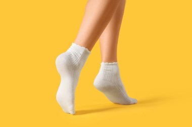 Beyaz çoraplı kadın sarı arka planda yürüyor.