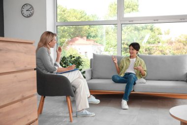 Ofiste genç bir çocukla konuşan kadın psikolog.