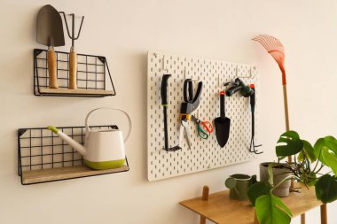 Çalışma odasındaki ışık duvarında bahçe aletleri olan tahta ve raflar