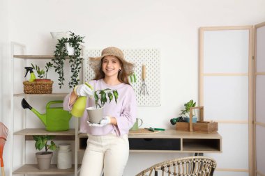 Kadın bahçıvan atölyede masa başında bitkileri ilaçlıyor.