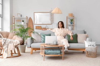 Oturma odasındaki rahat gri kanepede oturan güzel genç bayan.