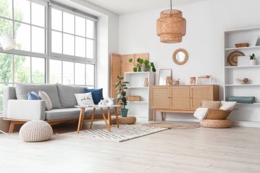 Pencerenin yanında gri kanepesi ve sehpası olan modern oturma odasının içinde.