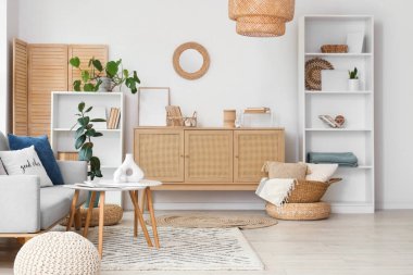 Gri kanepesi, sehpası ve ahşap dolabı olan aydınlık oturma odasının içi.