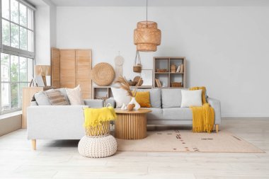 Gri kanepeleri ve pencerenin yanındaki kahve masası olan aydınlık oturma odasının içinde.