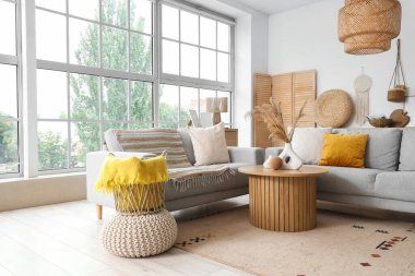 Gri kanepeleri ve pencerenin yanındaki kahve masası olan aydınlık oturma odasının içinde.