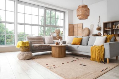 Gri kanepeleri ve pencerenin yanındaki kahve masası olan aydınlık oturma odasının içinde.