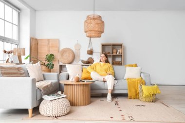 Gri kanepede oturan genç ve güzel bir kadın.