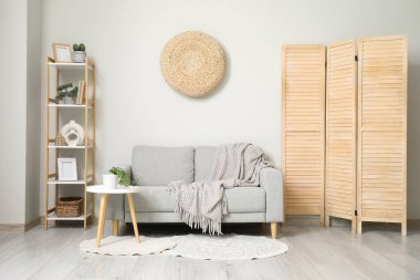 Şık bir oturma odasının içinde rahat bir kanepe ve katlanmış bir perde.