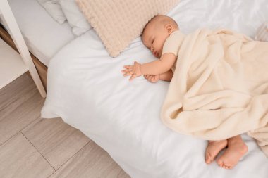 Yumuşak battaniyeli şirin küçük bebek evde yatakta uyuyor.