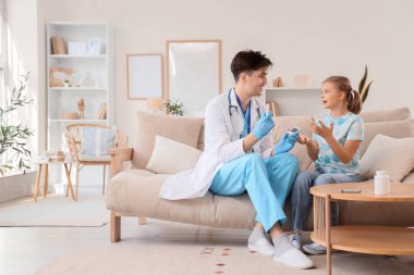 Doktor diyabetik kız evdeki kanepede glukometreden bahsediyor.