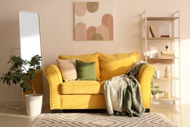 Rahat sarı kanepesi, aynası ve raf ünitesi olan şık bir oda.