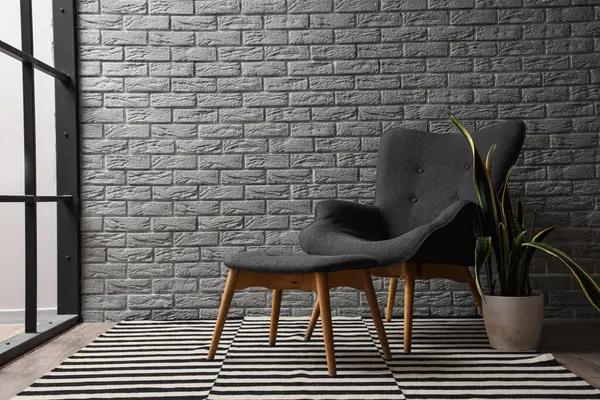 Çizgili halısı, koltuğu ve bitkisi olan oturma odası.