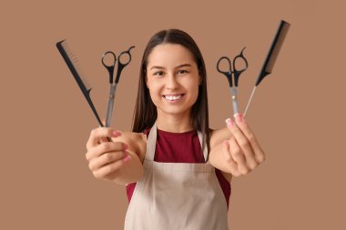 Kahverengi arka planda makasları ve tarakları olan kadın kuaför