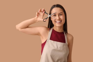 Kahverengi arka planda makaslı kadın kuaför