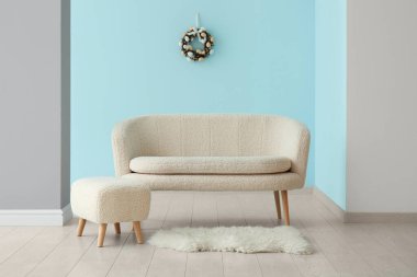 Mavi duvarda güzel Paskalya çelengi ve şık oturma odasında rahat bir kanepe.