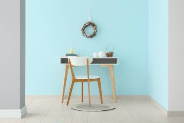 Güzel Paskalya çelengi, çalışma odasının yanındaki mavi duvarda yumurtalarla süslenmiş.