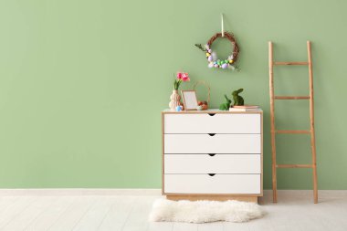 Odada yumurta ve çekmecelerle süslenmiş güzel Paskalya çelengi.