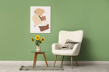 Oturma odasındaki masada güzel ayçiçekleri olan koltuk ve vazo.