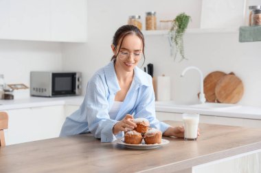 Genç bayan mutfaktaki masadan lezzetli çörekleri alıyor.