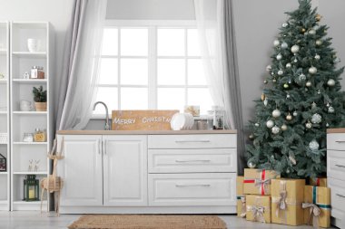İçinde Noel ağacı, raf ünitesi ve tezgahlar olan aydınlık mutfağın içi.