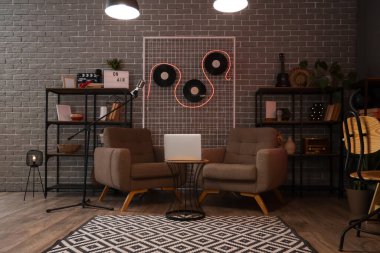 Masada koltukları ve dizüstü bilgisayarı olan Dark Podcaster 'ın stüdyosu.