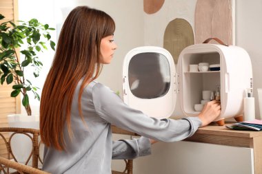 Evdeki buzdolabından kozmetik ürünleri alan güzel genç bir kadın.