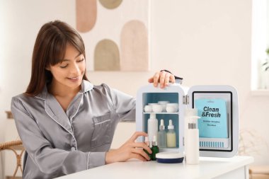 Evdeki buzdolabından kozmetik ürünleri alan güzel genç bir kadın.