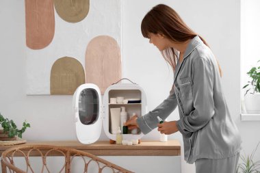 Evdeki buzdolabından kozmetik ürünleri alan güzel genç bir kadın.