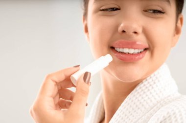 Güzel genç bir kadın arka planda dudak kremi sürüyor. Yakın plan.