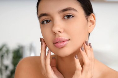 Evde yumuşak dudakları olan güzel genç bir kadın, yakın plan.