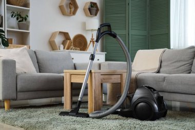 Oturma odasındaki masanın yanındaki modern elektrikli süpürge.