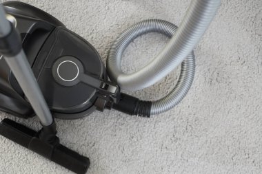 Halıda modern elektrikli süpürge, üst manzara.