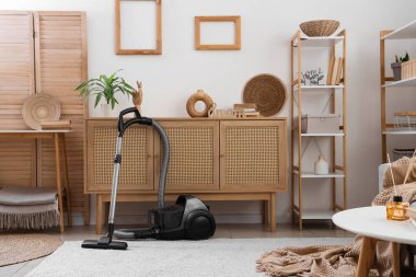 Elektrik süpürgesi, klozet ve raf üniteleriyle aydınlık oturma odasının içinde.