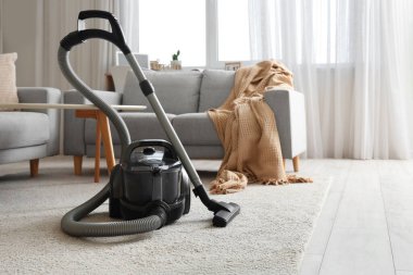 Oturma odasındaki halının üstünde modern elektrikli süpürge.