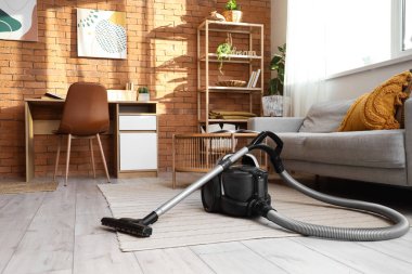 Oturma odasındaki halının üstünde modern elektrikli süpürge.