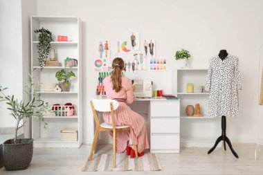 Atölyede arka planda çalışan kadın terzi.