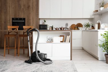 Elektrik süpürgesi, masa ve tezgahlı mutfağın içi.